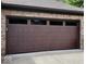 Close-up of a rich brown garage door with window insets, complementing the brick exterior of the home at 1102 Redwood Dr, Brownsburg, IN 46112