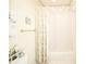 Well-lit bathroom with a floral shower curtain, neutral striped wallpaper, and charming decorative touches at 1105 Deer Creek Dr, Anderson, IN 46011