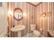 Charming powder room with pedestal sink, decorative mirror, and unique wallpaper at 1105 Deer Creek Dr, Anderson, IN 46011