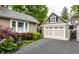 Attached garage with a basketball hoop, beautiful landscaping, and dark asphalt driveway at 114 E 44Th St, Indianapolis, IN 46205