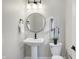 Bright powder room featuring pedestal sink, modern fixtures, and decorative mirror at 1429 Deloss St, Indianapolis, IN 46201