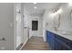 Elegant bathroom features a blue vanity, grey walls, modern mirrors, and wood-look flooring at 19570 Forsythe Dr, Noblesville, IN 46060