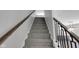 Carpeted staircase with dark wood railing and iron balusters leads to the upper level at 19570 Forsythe Dr, Noblesville, IN 46060