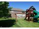 Spacious backyard with a brick home, patio, seating, and play structure for outdoor enjoyment at 2219 Stone Manor Ct, Avon, IN 46123