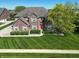 Charming two-story brick home with manicured lawn, mature tree, and inviting red front door at 2219 Stone Manor Ct, Avon, IN 46123