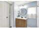 Bathroom featuring a light wood vanity with a round mirror and a white door and window at 2303 Midway St, Columbus, IN 47201