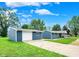 Exterior view of a well-maintained blue home with a detached garage, blue skies, and lush lawn at 2303 Midway St, Columbus, IN 47201