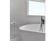 Close up of a sleek white freestanding bathtub under a window in a modern bathroom at 28 Hudson Bay Ln, Greenwood, IN 46142