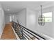 A naturally lit hallway with modern chandelier and black metal railings at 28 Hudson Bay Ln, Greenwood, IN 46142