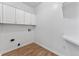 Bright laundry room with white cabinets, countertops, and wood-look floors at 28 Hudson Bay Ln, Greenwood, IN 46142
