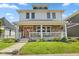 A two-story home with a welcoming front porch, stone accents, and an inviting orange front door at 2919 Macpherson Ave, Indianapolis, IN 46205