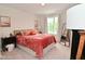 Bedroom with a coral-colored bedspread, bedside table, and natural light from the window at 3110 W New York St, Indianapolis, IN 46222