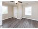 Inviting bedroom featuring wood-look flooring, neutral walls, a ceiling fan, and ample natural light through two windows at 3216 N Kenwood Ave, Indianapolis, IN 46208