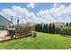 Green backyard featuring a well-maintained lawn, a wooden deck, and privacy trees along the fence at 3341 Enclave Xing, Greenwood, IN 46143