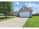 View of the home's long driveway and two car garage, surrounded by lush green lawn at 3341 Enclave Xing, Greenwood, IN 46143