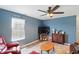 Cozy living room with blue walls, hardwood floors, ceiling fan, and a decorative cabinet at 3341 Enclave Xing, Greenwood, IN 46143