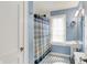 Bathroom features blue walls, white fixtures, black and white tile, and a window with blinds at 4527 Central Ave, Indianapolis, IN 46205