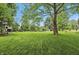 Wide shot of backyard featuring large shade tree and a spacious, level lawn at 5129 E 69Th St, Indianapolis, IN 46220