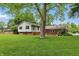Wide shot of the backyard featuring large shade tree, lawn, and brick house and siding at 5129 E 69Th St, Indianapolis, IN 46220