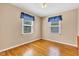 A bright bedroom showcases hardwood flooring, two windows, and potential for a cozy atmosphere at 518 N Carr Rd, Plainfield, IN 46168