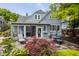 Backyard patio featuring an outdoor dining set, lounge chair, flower beds, and lush trees at 5219 N New Jersey St, Indianapolis, IN 46220