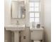 Clean bathroom with a pedestal sink, toilet, and a bright window providing natural light at 5219 N New Jersey St, Indianapolis, IN 46220