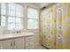 Bright bathroom featuring a white vanity and a shower with a yellow and gray floral patterned curtain at 5219 N New Jersey St, Indianapolis, IN 46220