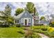 Charming blue bungalow with a brick chimney, garden landscaping, and walkway leading to the front entrance at 5219 N New Jersey St, Indianapolis, IN 46220