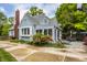 Landscaped backyard featuring a sunroom, stone patio, flowering bushes, and a brick chimney at 5219 N New Jersey St, Indianapolis, IN 46220