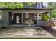 Charming back porch with a black brick wall, wood flooring, cozy seating, and a wood pile for the fireplace at 5280 N Capitol Ave, Indianapolis, IN 46208