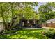 Backyard view showcases a well-maintained lawn, mature trees, a covered porch, and a private setting at 5280 N Capitol Ave, Indianapolis, IN 46208