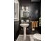 Stylish powder room featuring dark walls, pedestal sink, and modern fixtures at 5280 N Capitol Ave, Indianapolis, IN 46208