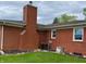 Rear exterior view with chimney, showing brick siding, roof, and small garden area at 5457 W 900 North, McCordsville, IN 46055