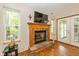 Close up on the fireplace, featuring wood burning insert, brick surround, and access to backyard through french doors at 6138 Bartley Ct, Indianapolis, IN 46236