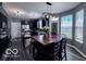 Eat-in kitchen with black cabinets, granite countertops, stainless appliances, wood floors, and large windows at 6155 W Bayfront, McCordsville, IN 46055