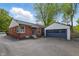 Quaint brick house with a blue door and detached garage, long driveway at 7060 N Park Ave, Indianapolis, IN 46220