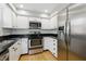 Updated kitchen features stainless steel appliances, black countertops, white cabinetry, and hardwood floors at 7060 N Park Ave, Indianapolis, IN 46220