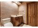 Powder room featuring wallpaper, a vanity with marble countertop, a toilet, and wood trim at 7406 N Washington Blvd, Indianapolis, IN 46240