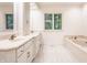 Bright bathroom featuring dual sinks, a soaking tub, and a large window with a view at 7406 N Washington Blvd, Indianapolis, IN 46240