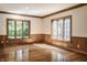 Sun-filled room with wainscoting, hardwood floors, and large windows overlooking greenery at 7406 N Washington Blvd, Indianapolis, IN 46240