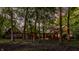View of the Tudor-style home through the trees with glowing lights adding warmth at 7406 N Washington Blvd, Indianapolis, IN 46240