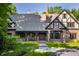 Charming Tudor-style home featuring a brick facade, inviting driveway, and professionally landscaped yard at 7406 N Washington Blvd, Indianapolis, IN 46240