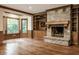 Bright living room with a stone fireplace, built-in shelves, hardwood floors, and bay windows at 7406 N Washington Blvd, Indianapolis, IN 46240