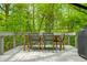 Outdoor dining area on deck offers serene treetop views with wooden table and metal framed chairs at 7595 Heather Dr, Nineveh, IN 46164