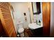 Compact bathroom with a modern vanity, toilet, and a wooden louvered door for ventilation at 76 Manhattan Ave, Indianapolis, IN 46241