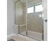 Modern bathroom with a glass shower door, neutral tiling, and a built-in bench at 8245 Bostic Dr, Fishers, IN 46038