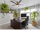 Inviting home office with leafy plants, a dark desk, and custom shelves displaying decorative items at 8245 Bostic Dr, Fishers, IN 46038