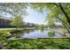View of pond surrounded by lush greenery with apartment buildings in the background at 8751 Jaffa Court East Dr # Apt 32, Indianapolis, IN 46260