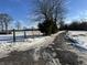Long driveway to property with winter foliage; a rustic wooden 