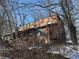 Charming home with wood siding and a quaint front porch, surrounded by bare winter trees and sitting atop a stone foundation at 8803 S Sleepy Hollow Rd, Waldron, IN 46182